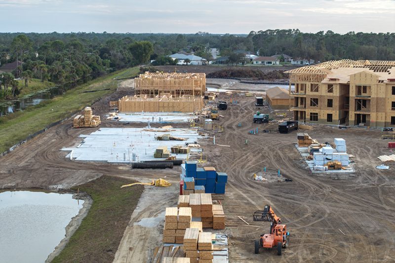 Unfinished frames of apartment condos with wooden roofs under construction. Development of residential housing in US suburbs. Real estate market in the USA